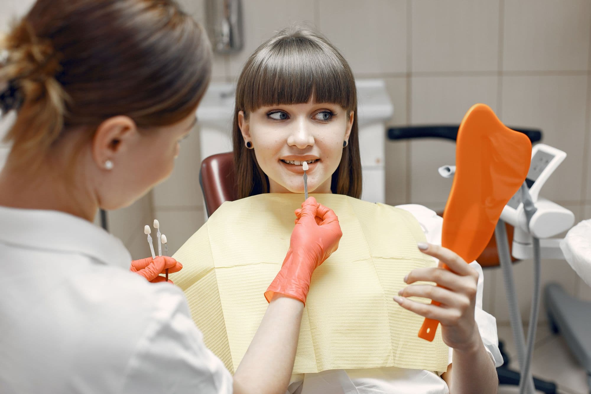 A dentist and a patient checking her smile in a mirror