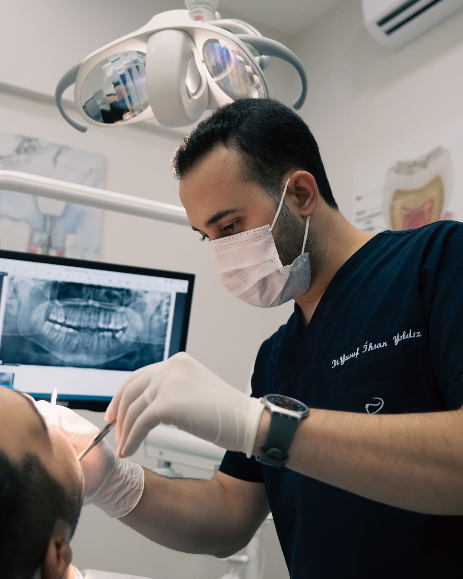 A dentist with a dental X-ray on screen